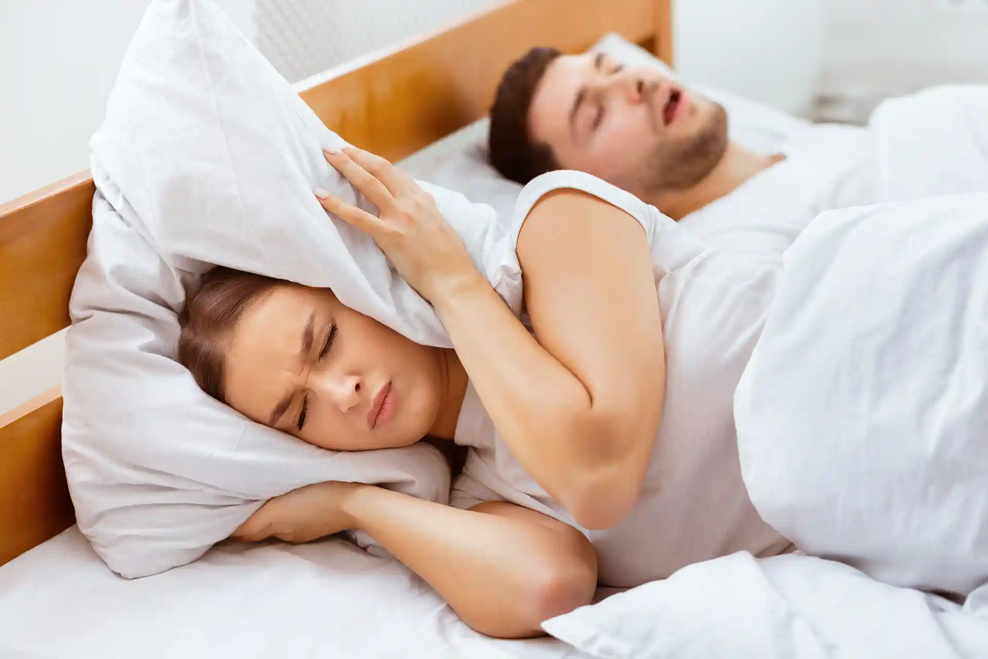 annoyed woman covering ears from snoring partner