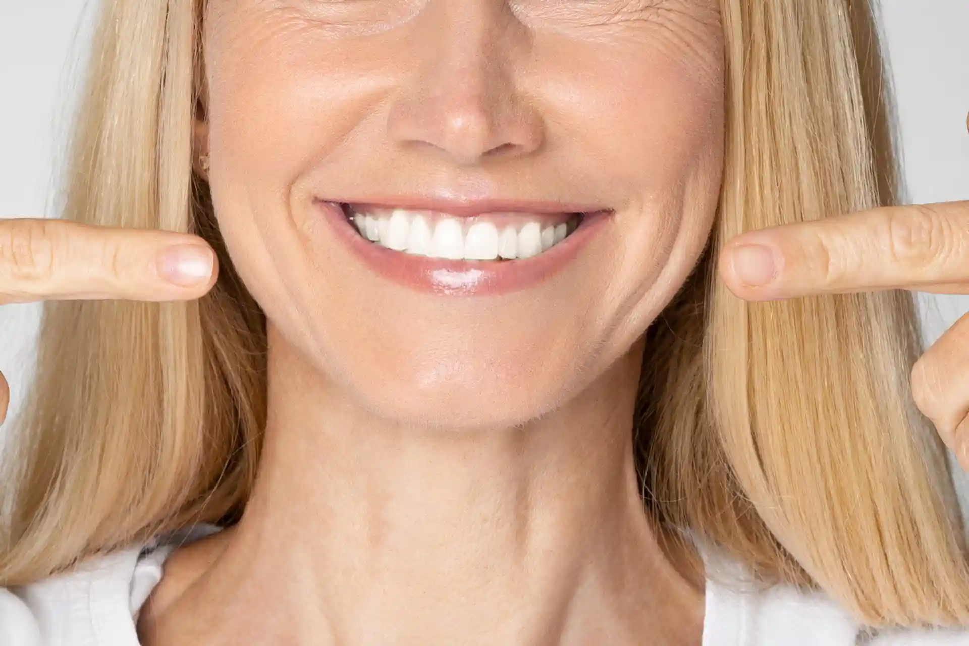 woman pointing at her white teeth